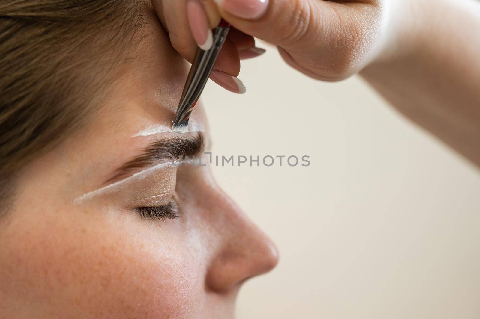 The master draws the shape of the eyebrows with white paint before coloring