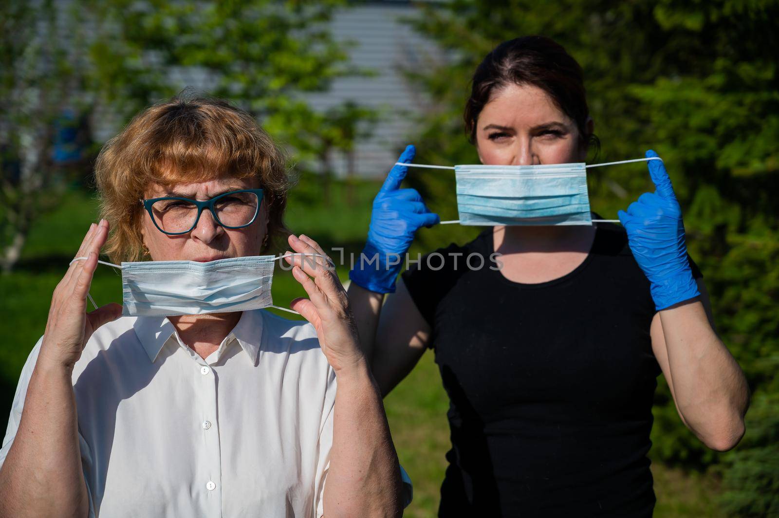 Mom and daughter put on medical masks against the spread of infection. Two elderly and middle-aged women are protected against coronavirus. by mrwed54