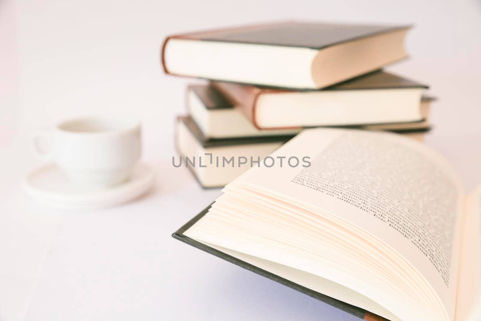 Stacked books next to cup of coffee on white background