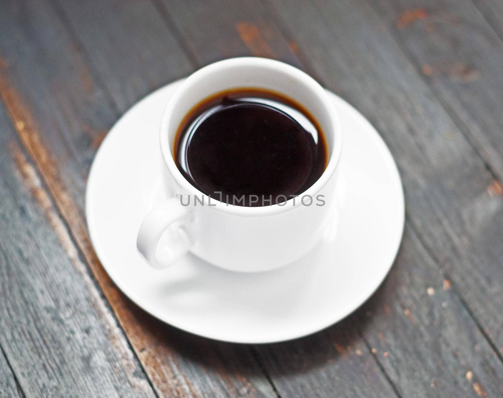 one white coffee cup with saucer on wooden background by andre_dechapelle