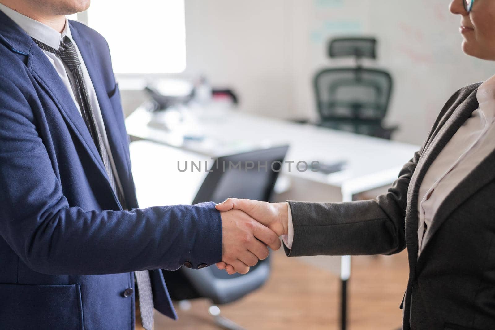 Handshake business man and woman at the conclusion of a successful transaction. Office staff in suits during a greeting. Successful job interview. by mrwed54