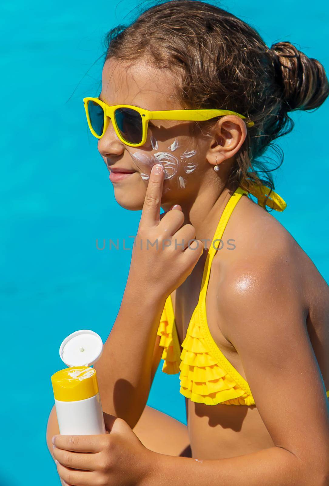 Sunscreen near the pool on the face of the child. Selective focus. Kid.