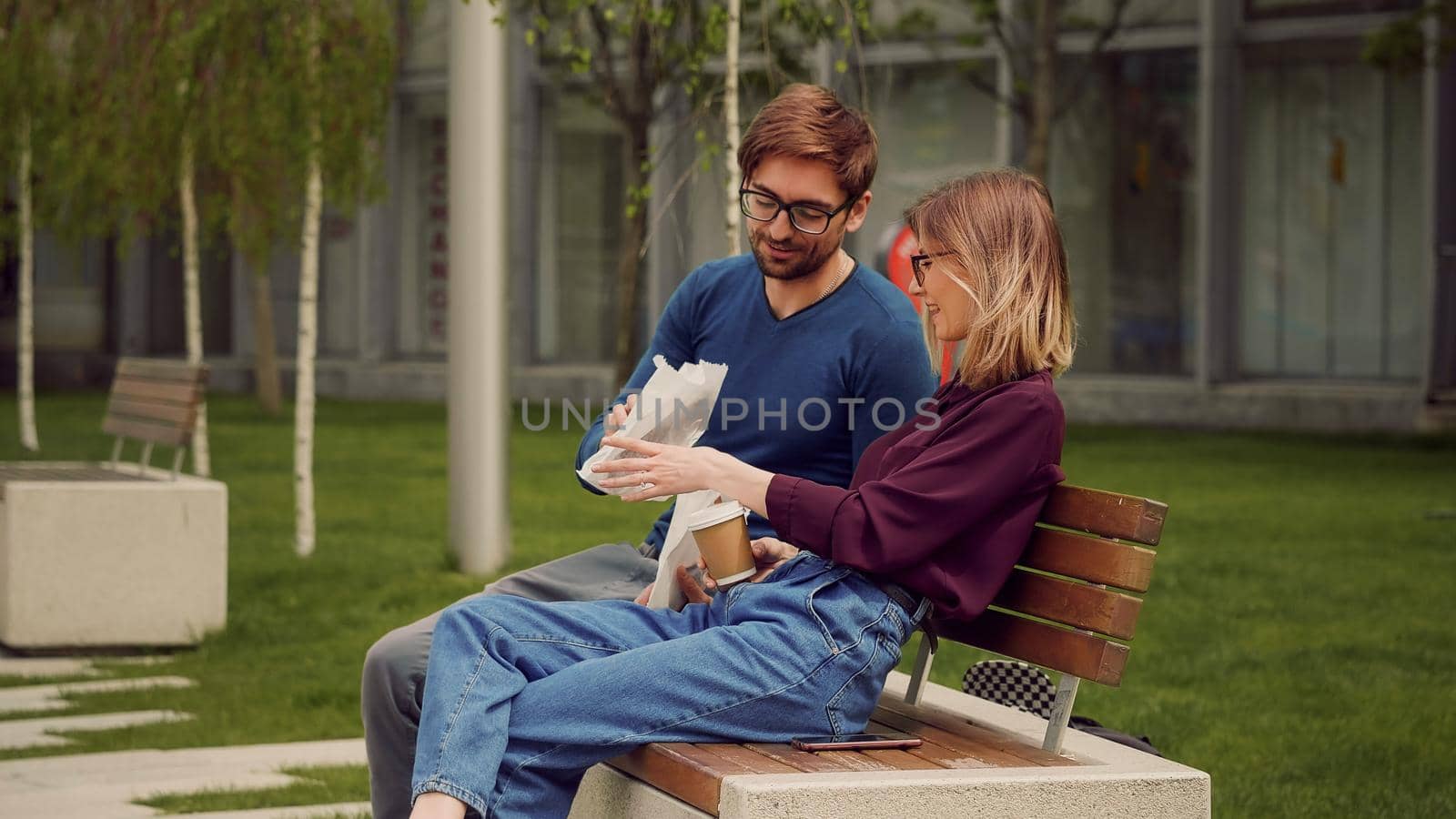 Young happy student colleagues during coffee break patio in the park. Friendly atmosphere outdoor.