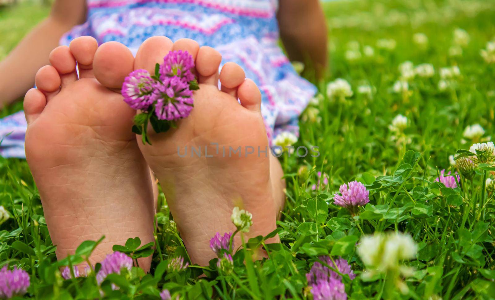 Children's feet with a pattern of paints smile on the green grass. Selective focus. nature.