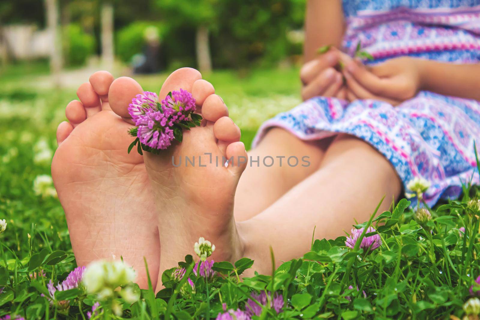 Children's feet with a pattern of paints smile on the green grass. Selective focus. by mila1784