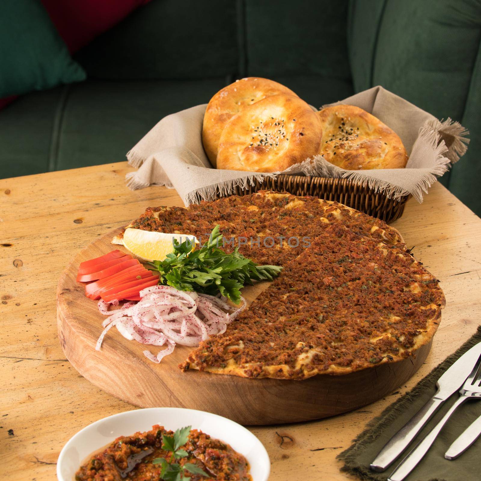 A close up shot of a lahmacun and a salad near basket of breads