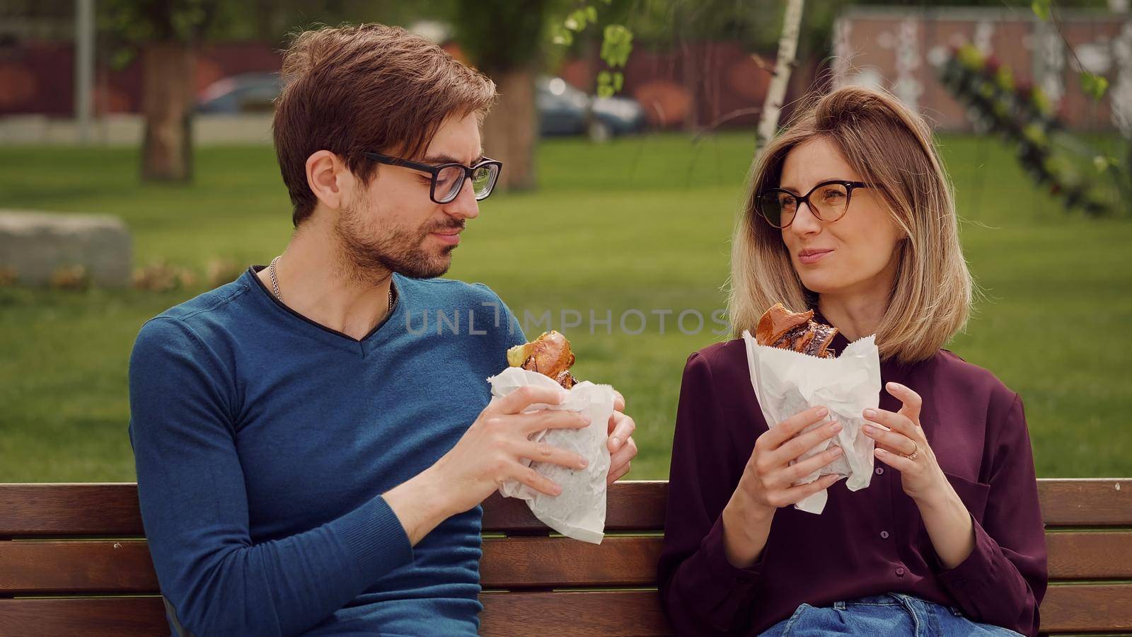 Two student eat buns outdoors during courses break. by RecCameraStock