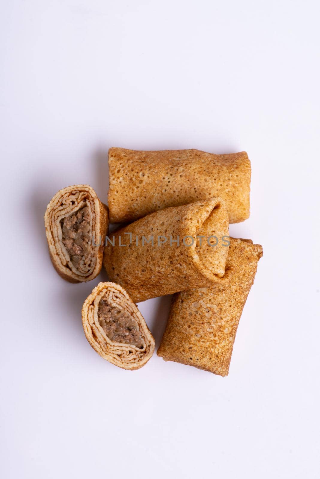 A vertical shot of stuffed pancakes with meat on a white background