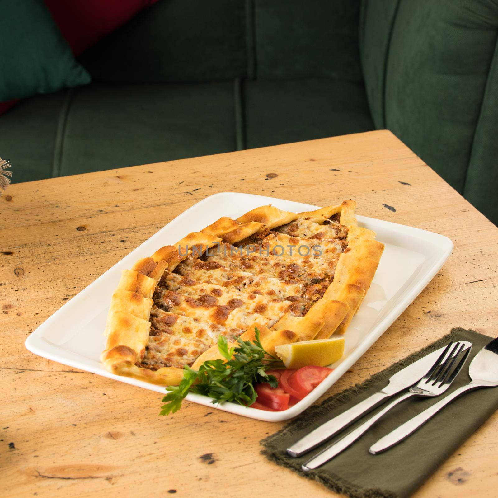 A traditional Turkish baked pide in a white plate on a wooden table
