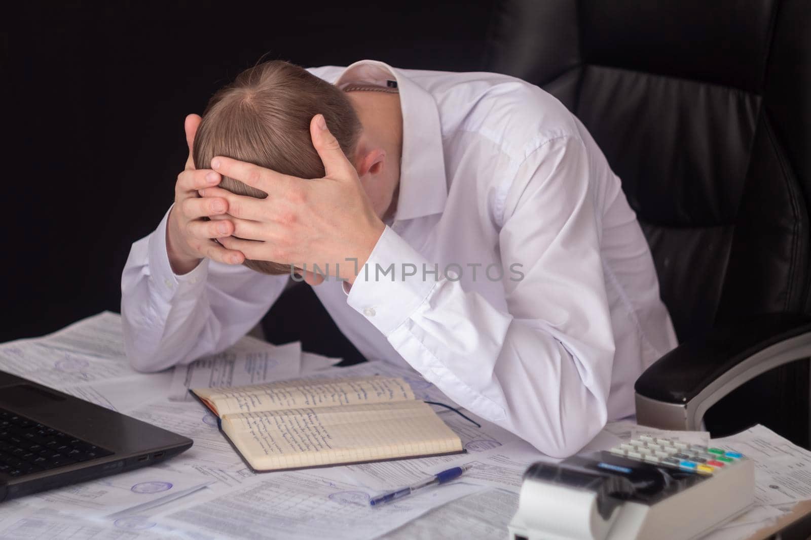 The state of crisis, failure and depression. Work with documents. Frustrated guy at the Desk with documents. Problems with documents, debts on loans and tax operations. Confiscation