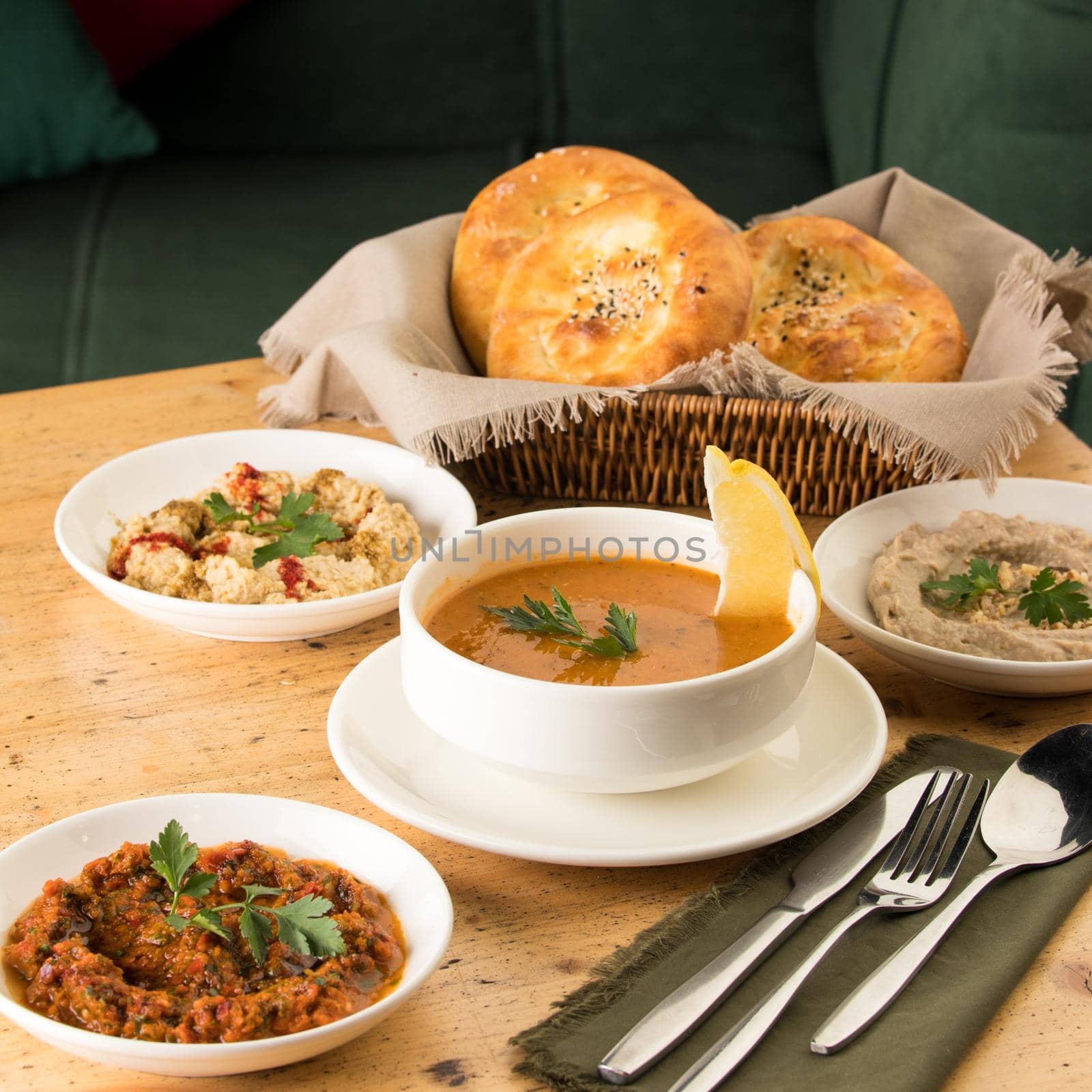 A closeup shot of a soup and appetizers near basket of breads