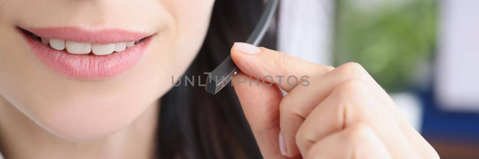 Close-up of female support service worker and small microphone for voice connection. Operator wear headset in office. Customer service, telesales concept