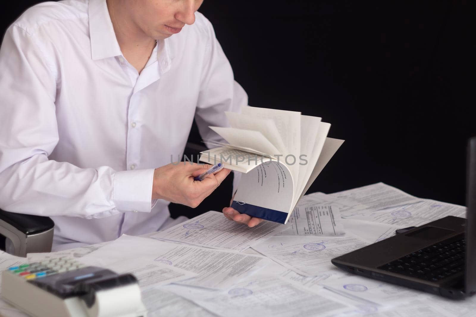 A businessman works with stocks, bonds, obligations, securities and documents in a night office. Fulfillment of obligations to work with documents in the office. Employee at a laptop in the office.