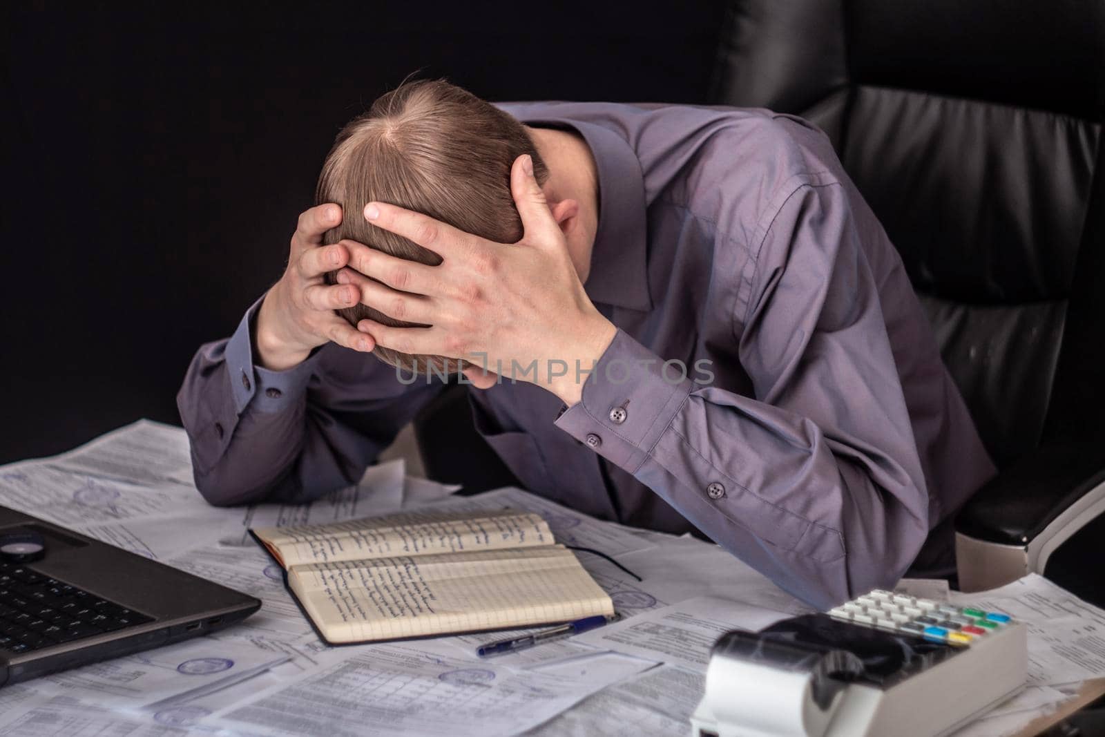 The state of crisis, failure and depression. Work with documents. Frustrated guy at the Desk with documents. Problems with documents, debts on loans and tax operations. Confiscation