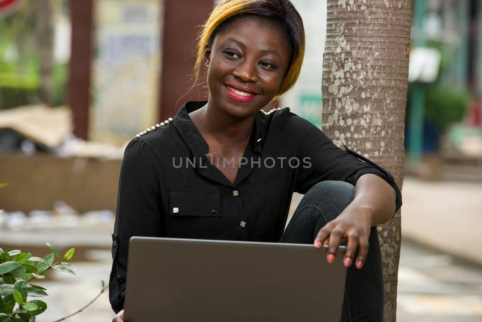 student sitting with laptop watching camera smiling.