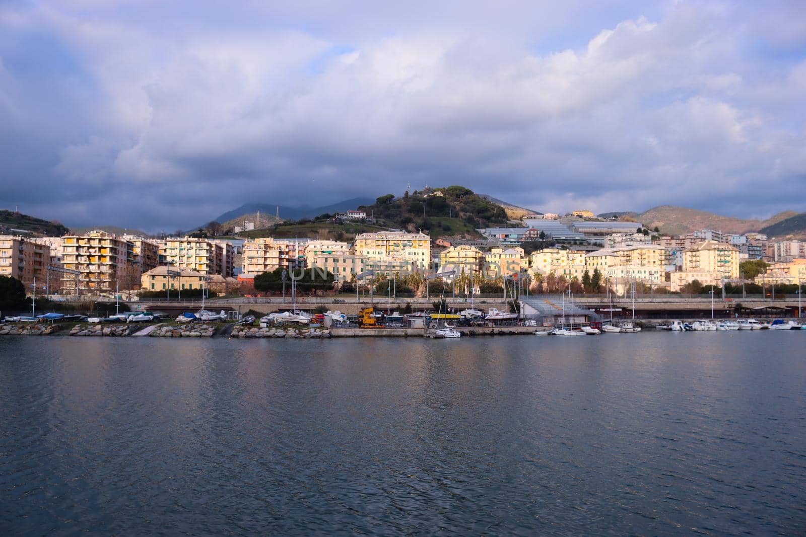 Genova, Italy- June 20,2022: Port of Porto Antico harbor with luxury  yachts and attractions, Bigo construction in historical centre of old european city Genoa with beautiful sunset reflection.