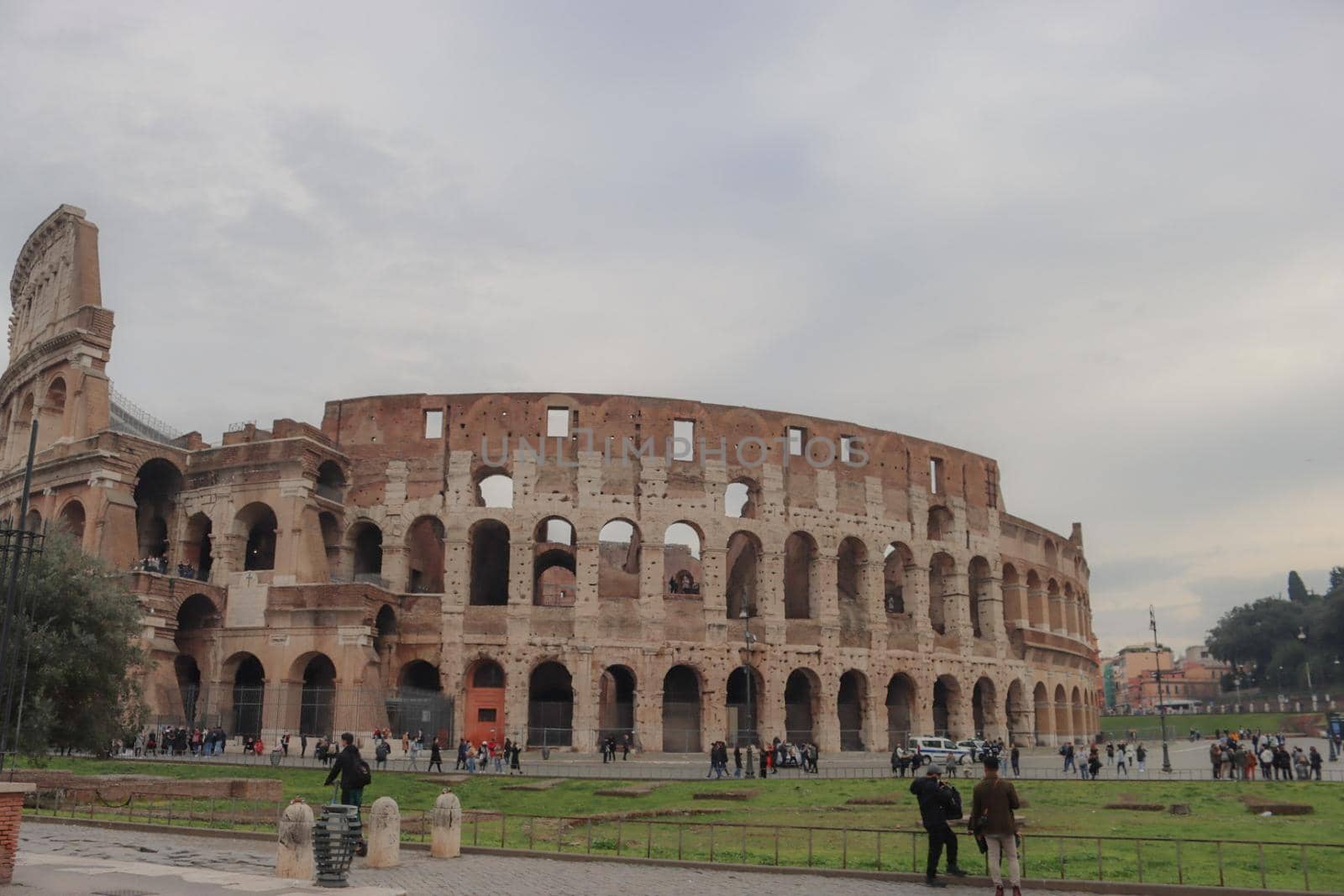 ROME, ITALY - February 05, 2022: Panoramic view around the Colosseum in city of Rome, Italy. Cold and gray sky in the background. Macro photography of the green parks with the old buildings.