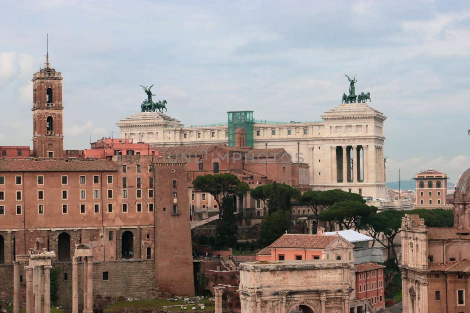 ROME, ITALY - February 05, 2022: Panoramic view around the Colosseum in city of Rome, Italy. Cold and gray sky in the background. Macro photography of the green parks with the old buildings.