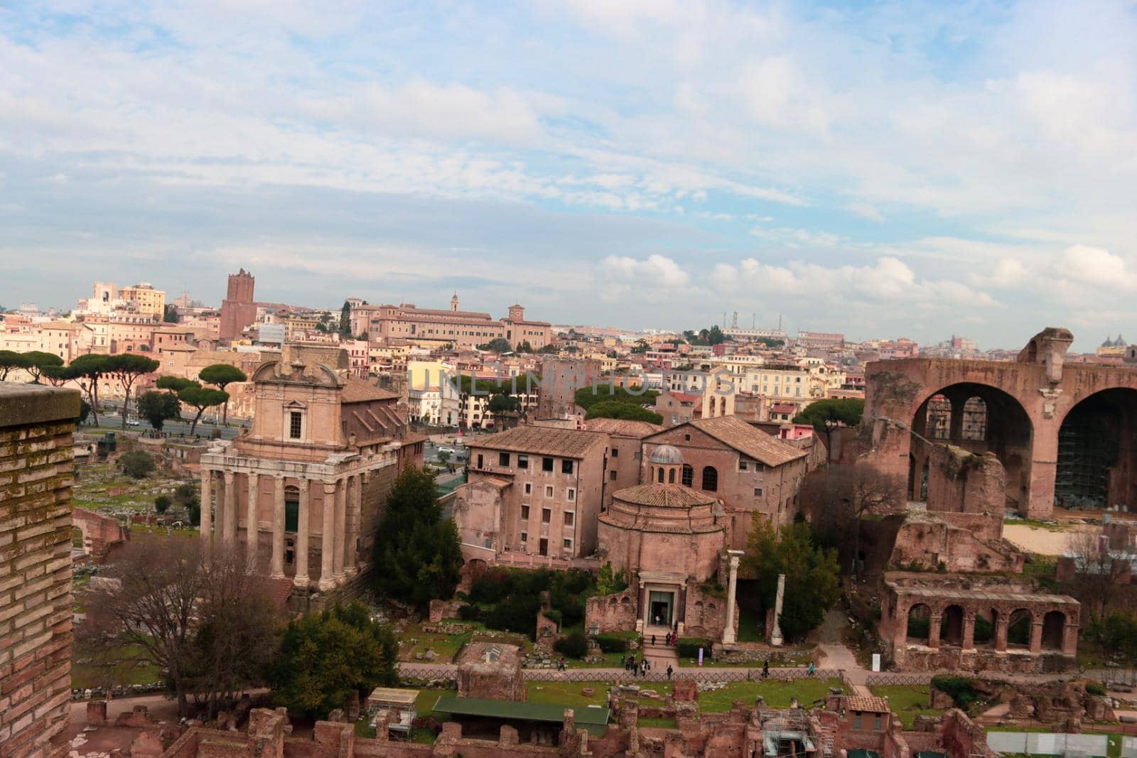 ROME, ITALY - February 05, 2022: Panoramic view around the Colosseum in city of Rome, Italy. Cold and gray sky in the background. Macro photography of the green parks with the old buildings.