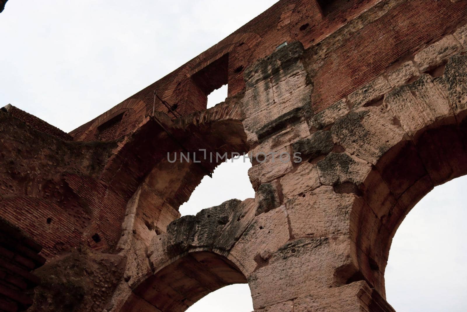 ROME, ITALY - February 05, 2022: Panoramic view around the Colosseum in city of Rome, Italy. Cold and gray sky in the background. Macro photography of the green parks with the old buildings.