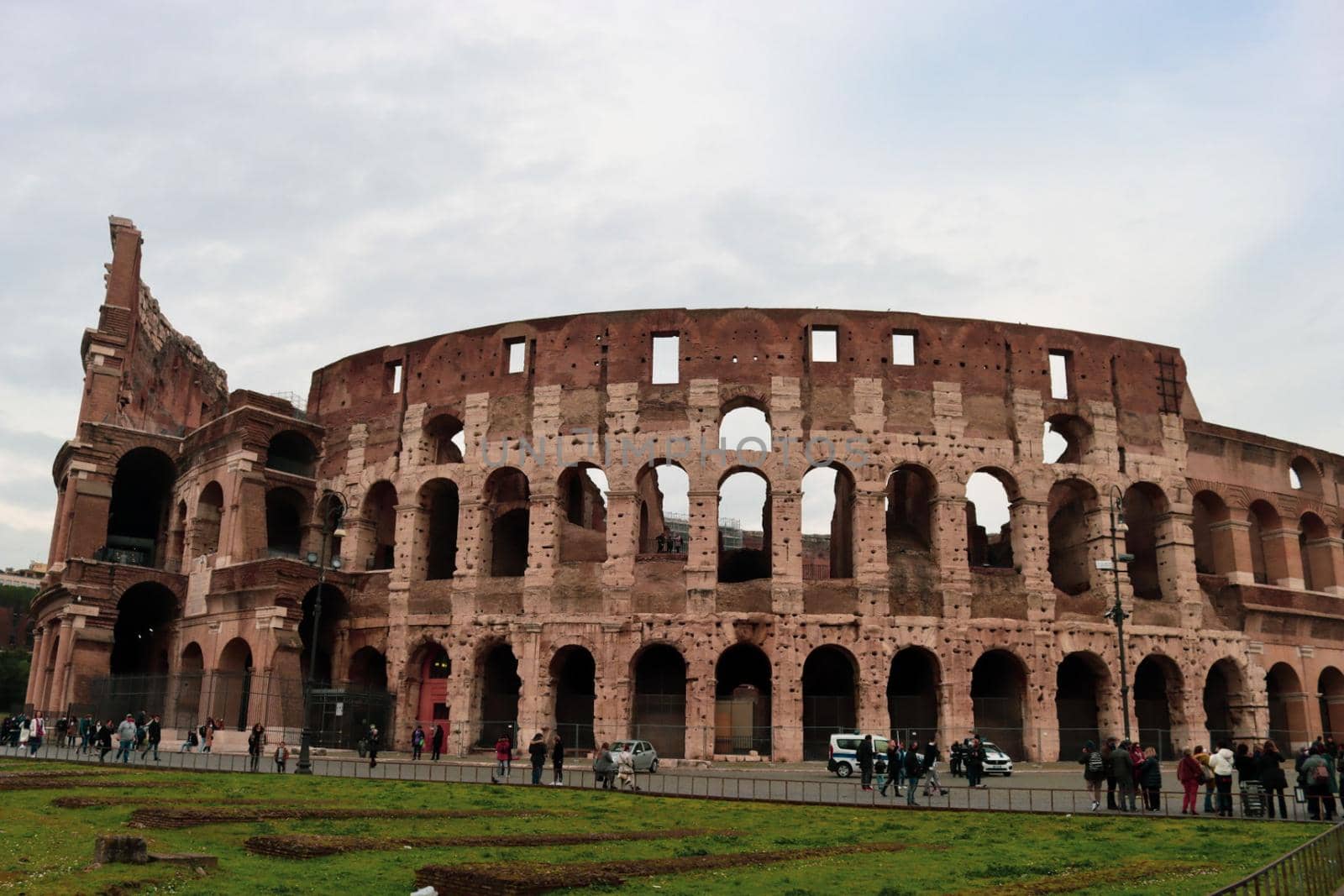 ROME, ITALY - February 05, 2022: Panoramic view around the Colosseum in city of Rome, Italy. Cold and gray sky in the background. Macro photography of the green parks with the old buildings.