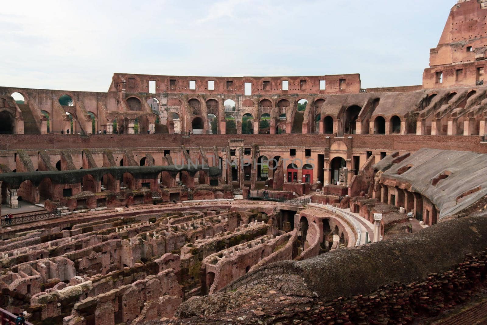 ROME, ITALY - February 05, 2022: Panoramic view around the Colosseum in city of Rome, Italy. Cold and gray sky in the background. Macro photography of the green parks with the old buildings.