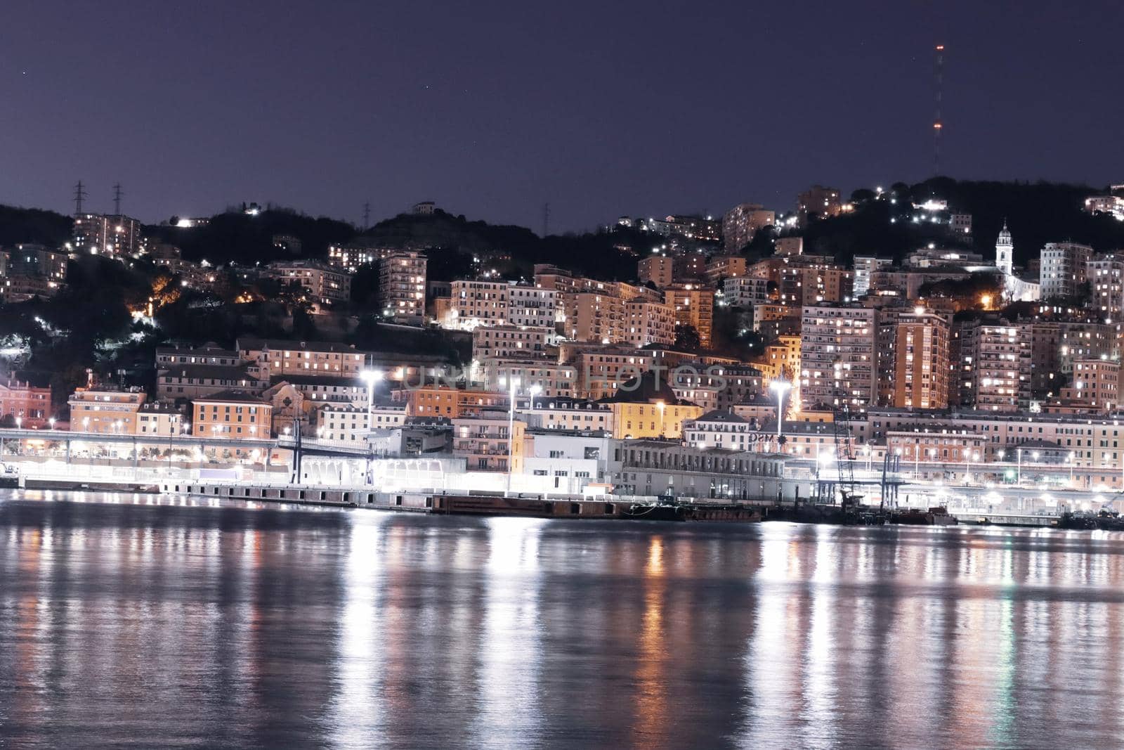 Genova, Italy - May 07, 2022: Panoramic view from the sea to the old town, and the port with beautiful sunset. Genoa bay, harbor, yacht at the pier.tourist destinations.