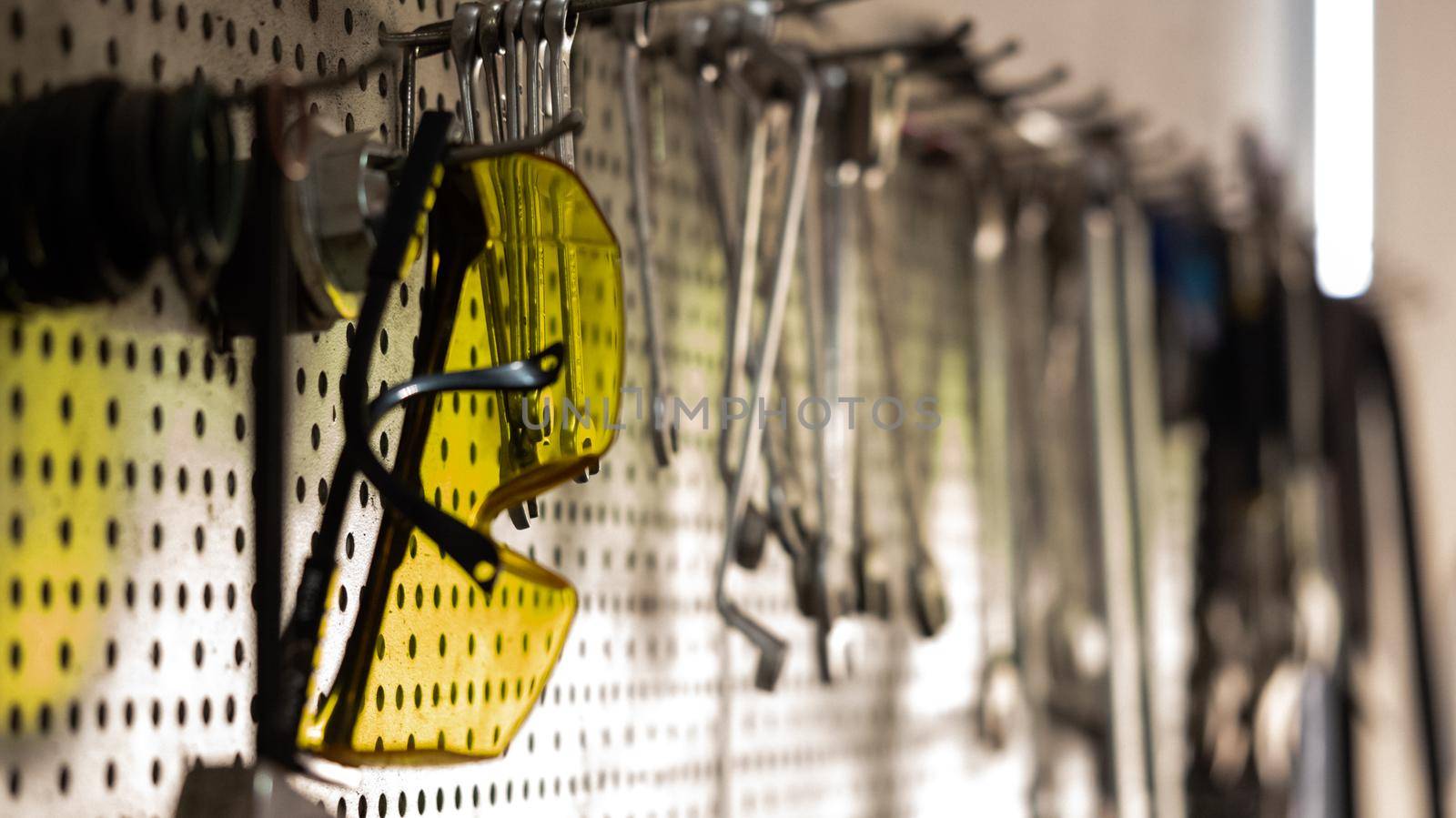 Goggles, various tools hanging on garage wall by RecCameraStock