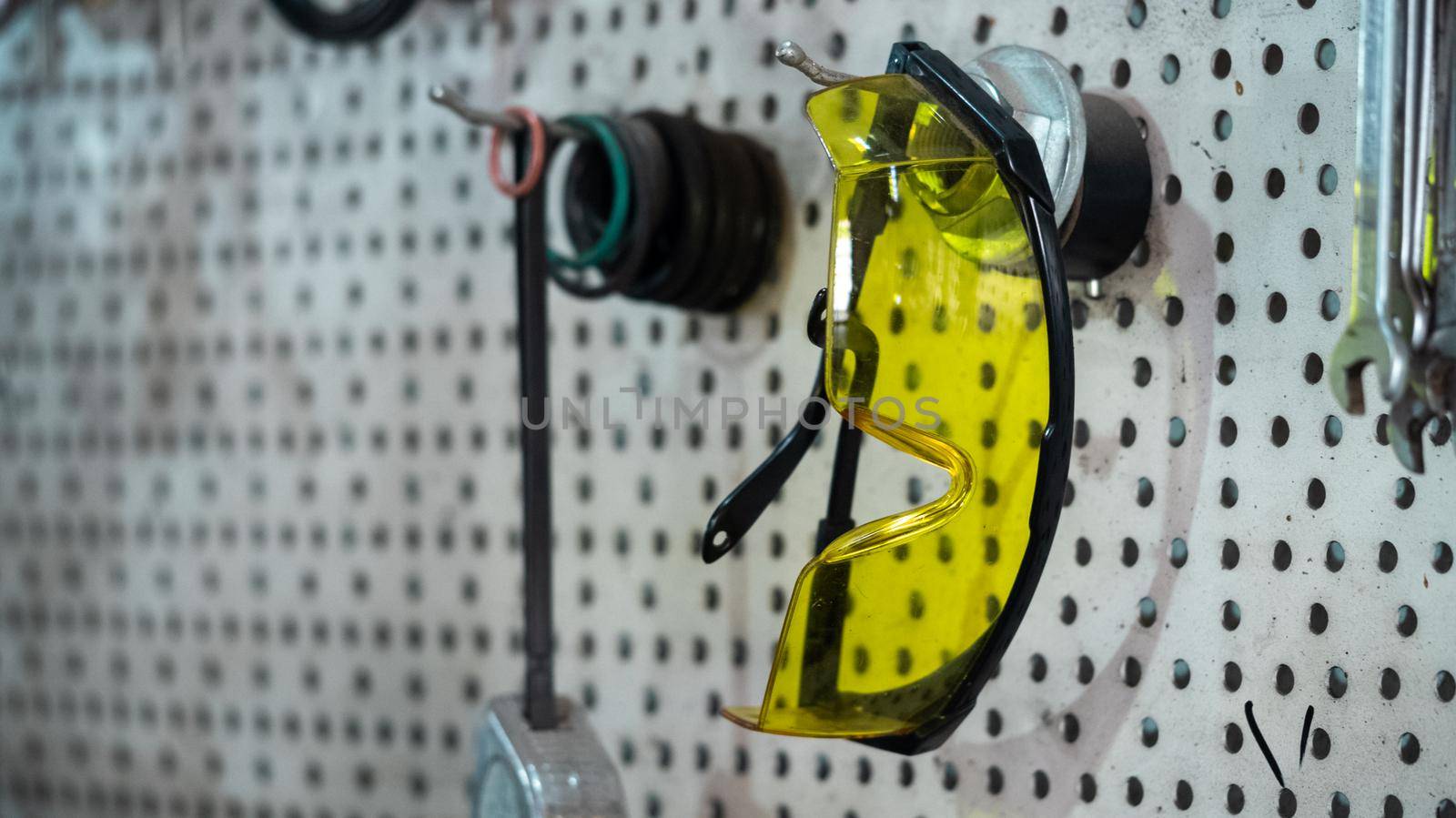 Yellow protection safety glasses. Goggles hanging on the wall of a car service. Garage tools.