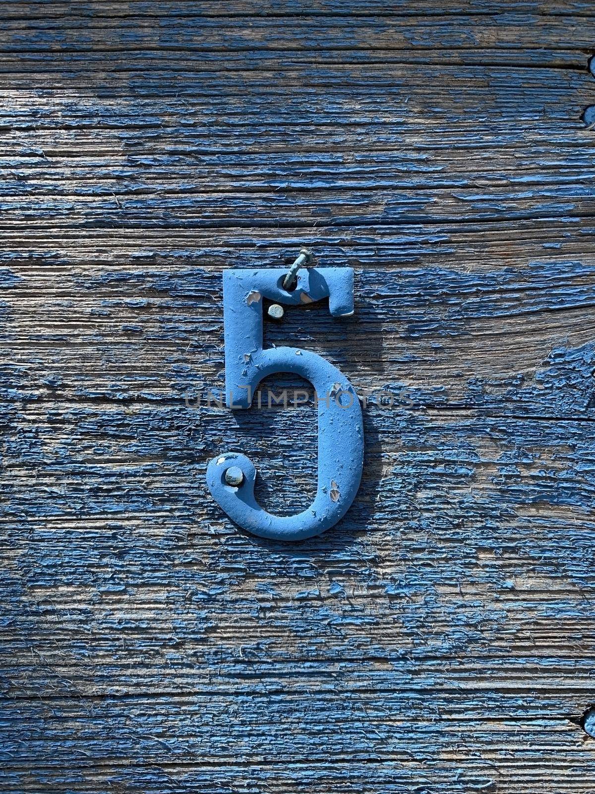 vertical photo of the number five nailed to the board