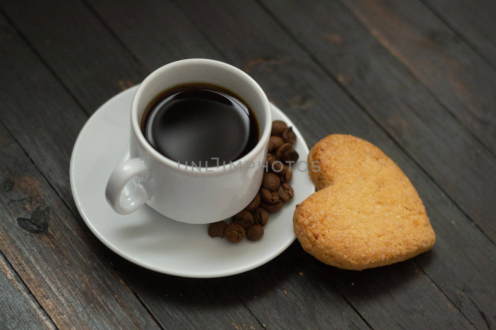 a cup of coffee with coffee beans and love cookie on wooden surface.Valentine day holiday by andre_dechapelle