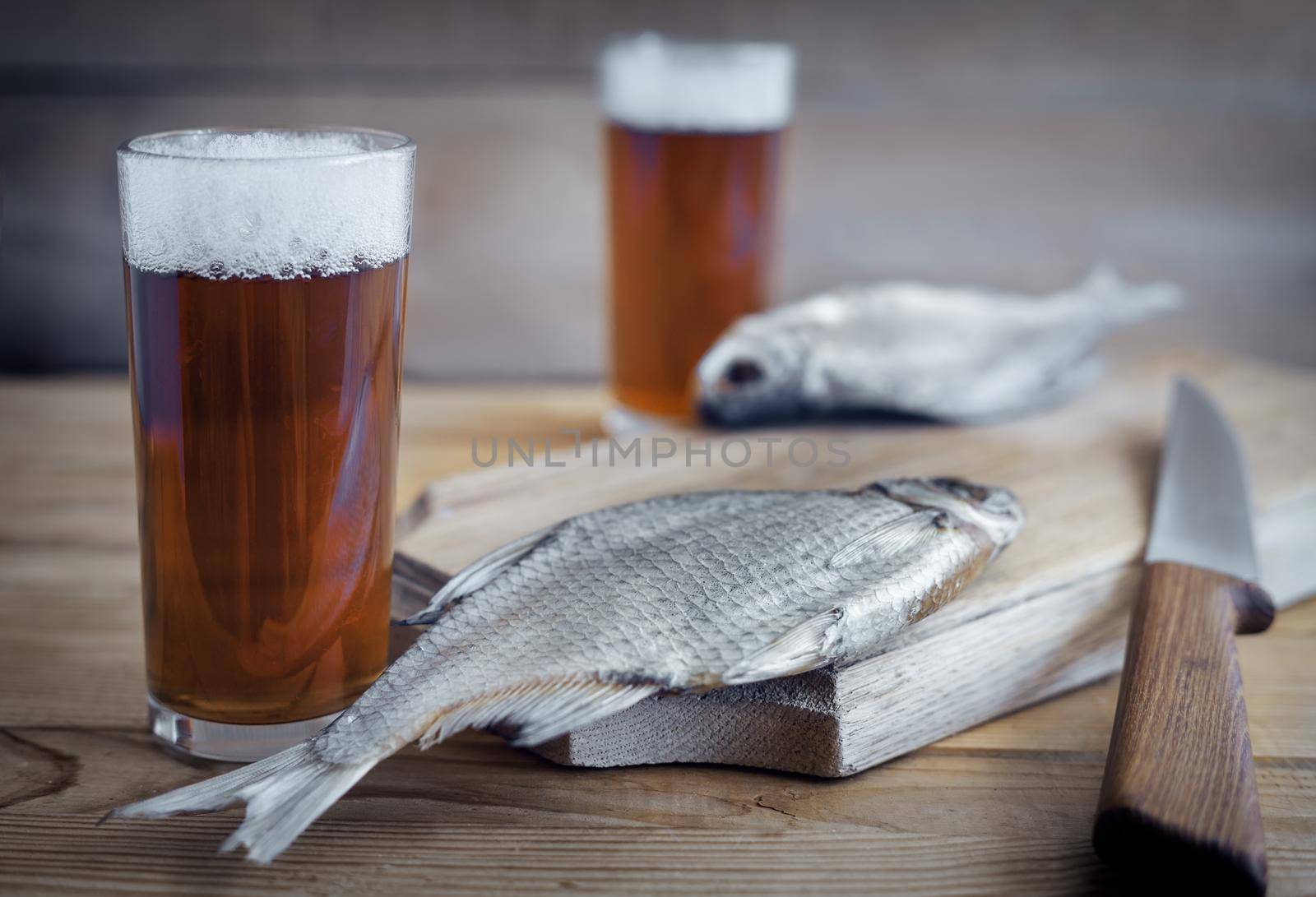 Two glasses of beer and dried fish . by georgina198