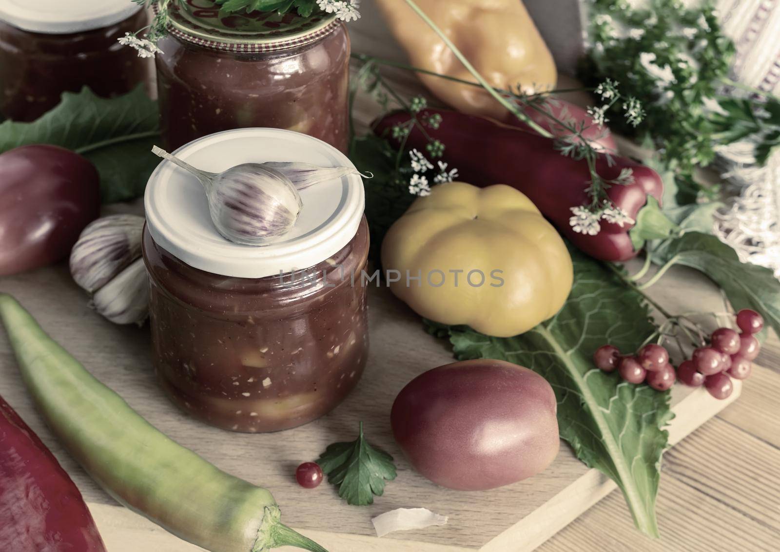 In glass jars Lecho of canned bell peppers and tomatoes, near fresh peppers and tomatoes