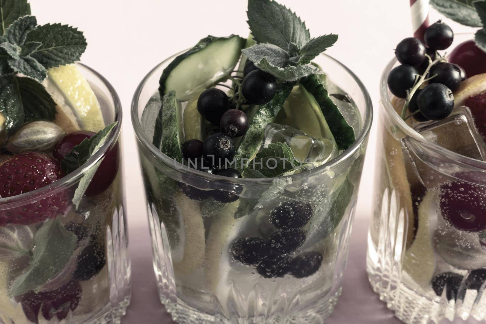 Summer refreshing cocktail of natural fruits and various berries with ice and mint leaves infused with water. Contains lemon, orange, strawberry, cherry, currant.