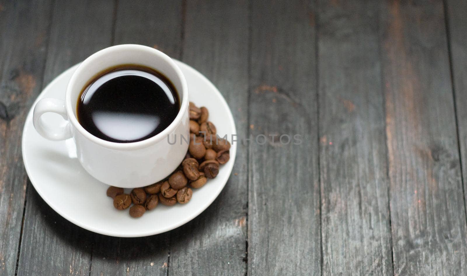 Top view, a cup of coffee with coffee beans on wooden background, copyspace.Morning coffee.