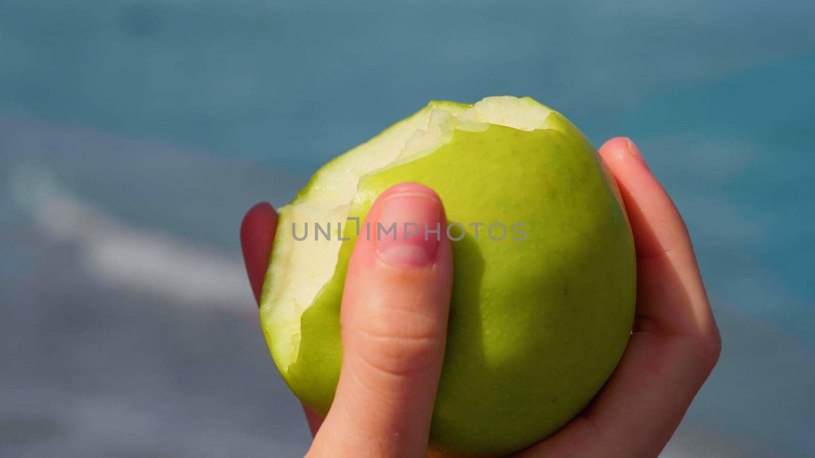 Woman eating apple, fruit. Healthy snack on summer. Close up ripe green apple