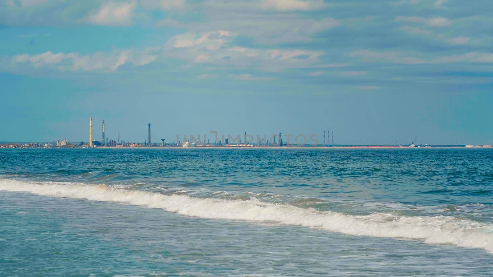 Industrial area on the Black Sea coast, Romania. Blue sky and clear water. Summer day on seashore. View of port, storage of petrochemical products.