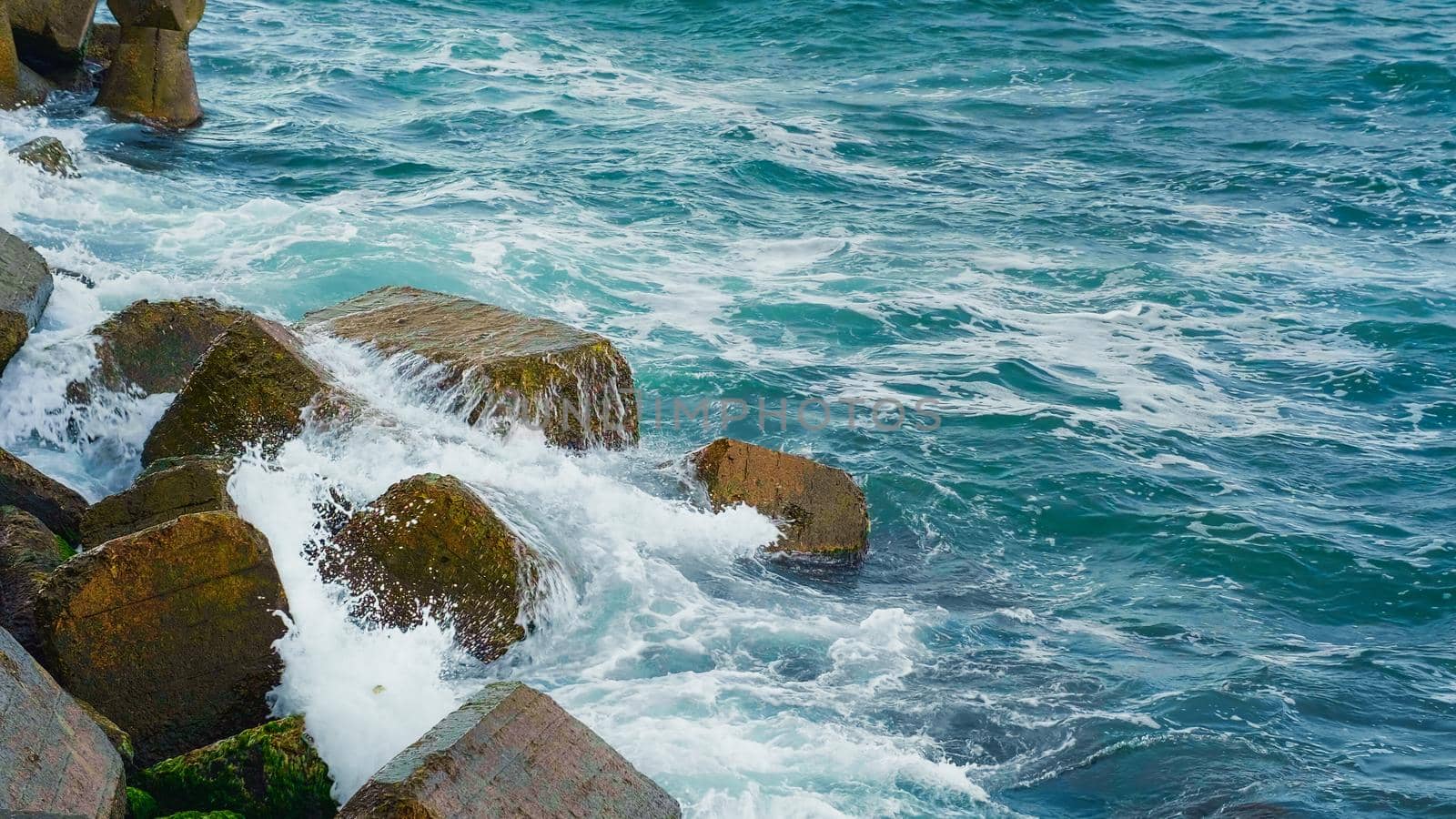 Blue clear sea water on the coastile breaking over rocks by RecCameraStock