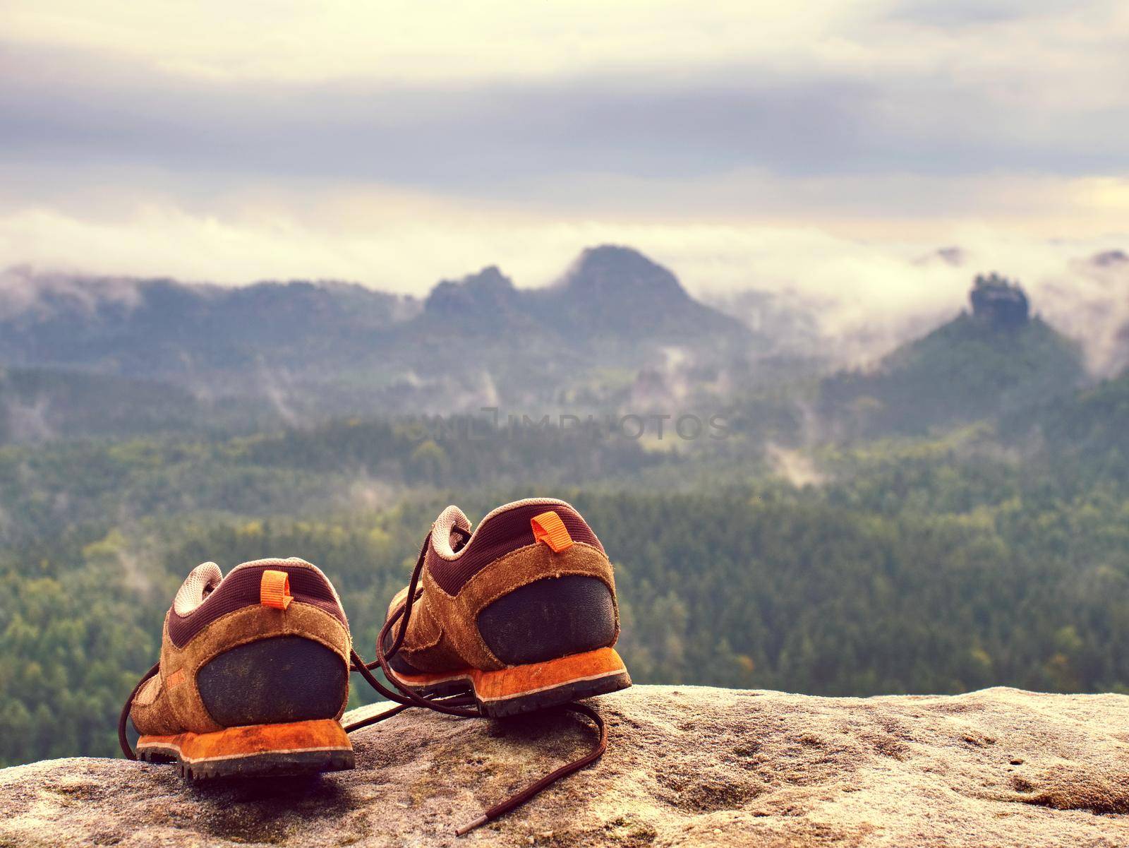 Brown hiking boots on rocks in front of mountain range by rdonar2