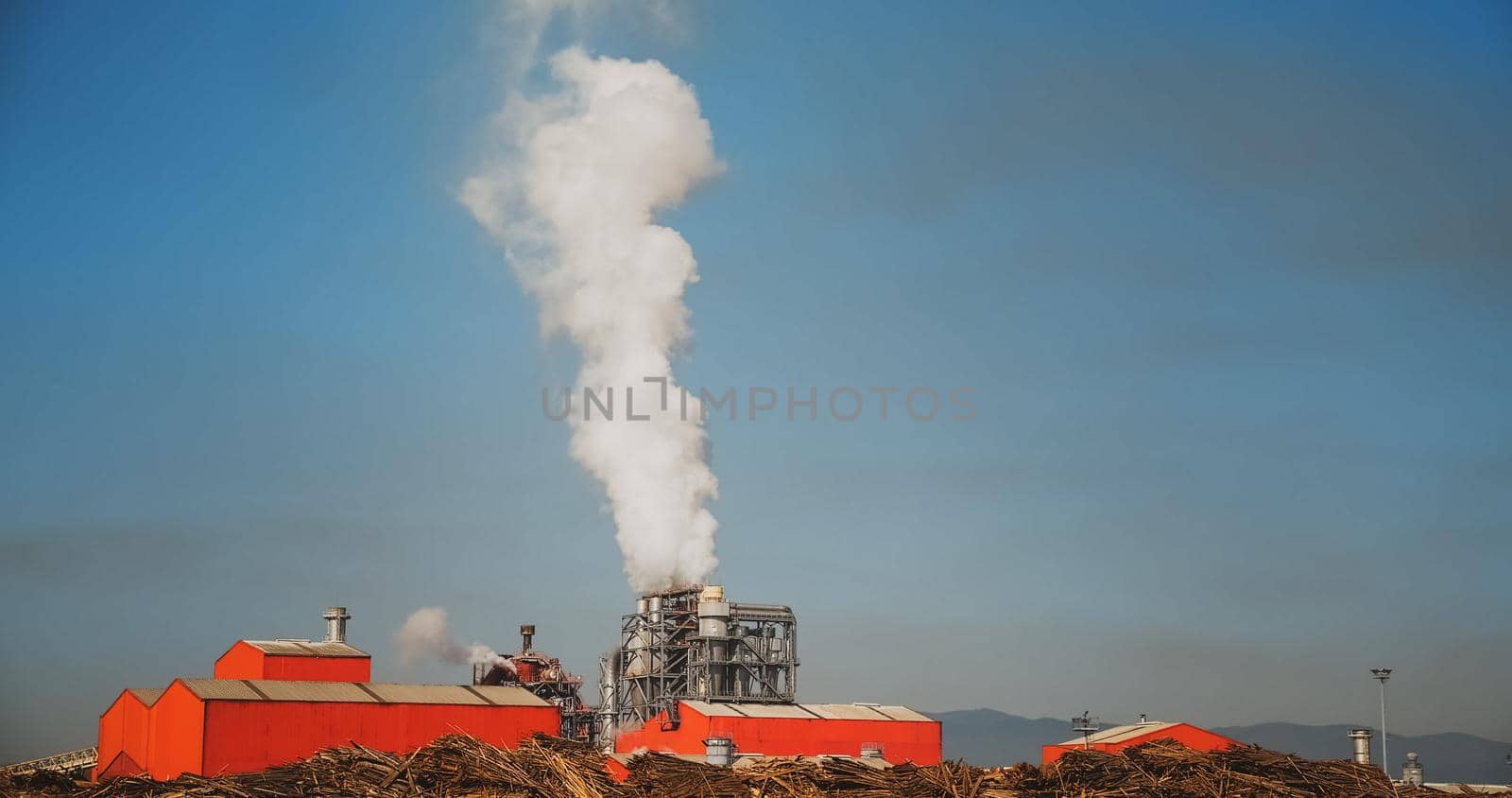 Wood processing plant pollutes the air with smoke coming from the pipe. Pollution of the environment a pipe with smoke. Ecological environment polliation.