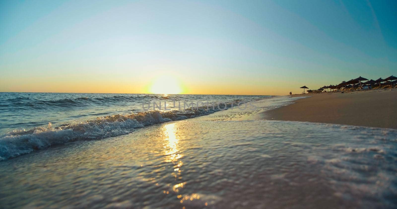 Beautiful scene sunset, tropical beach sea. Tourist destination in Tunisia, Africa. Close up shot of shining waves on seaside.