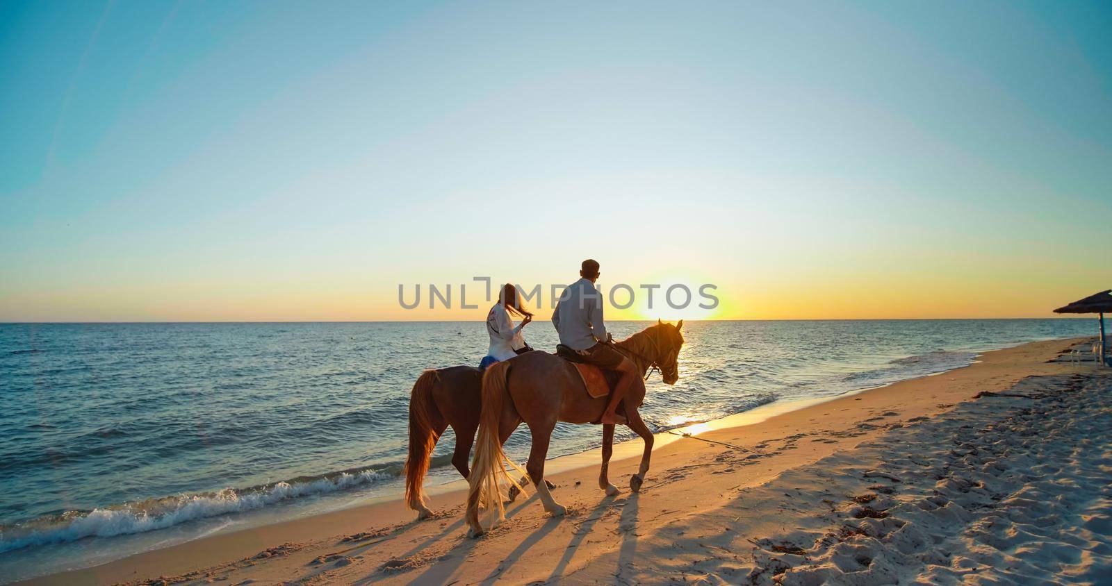 Monastir, Tunisia, 2022: Scenic, romantic view of a beach at sunset. Couple in love is enjoying holiday. Seashore with sun shining. Beautiful landscape, travel destination.