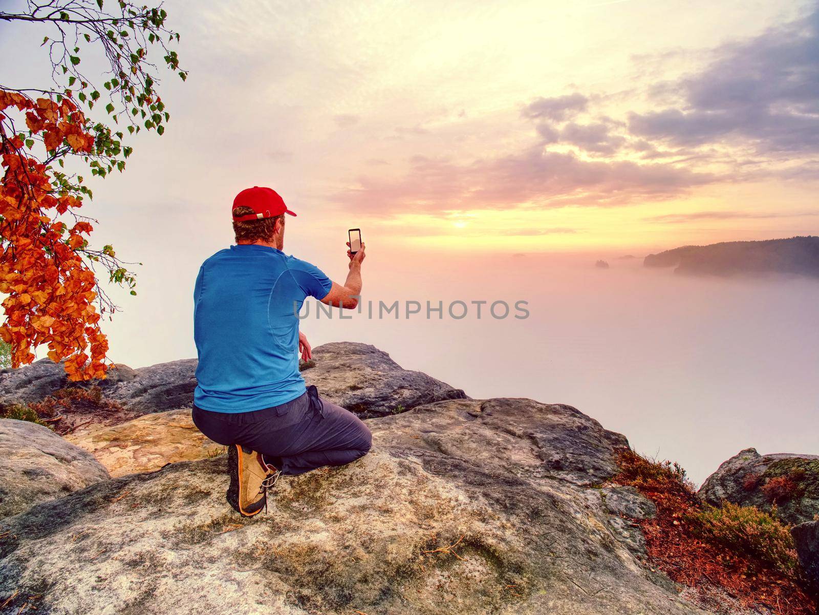 Male traveler using mobile cell phone sharing fall mountains landscape view for friend through scial network. 