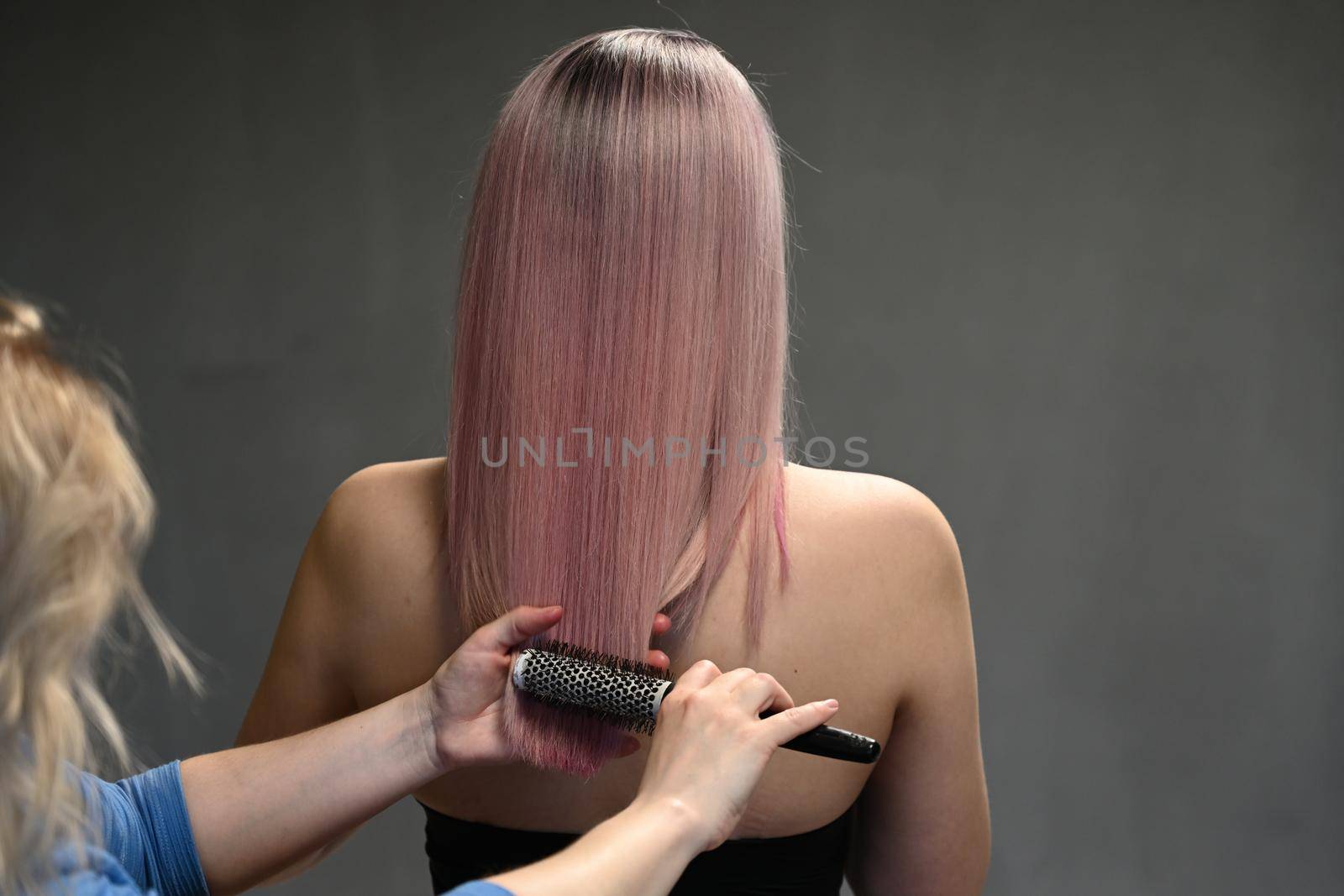 Hairdresser's hands combing model's dyed hair from behind