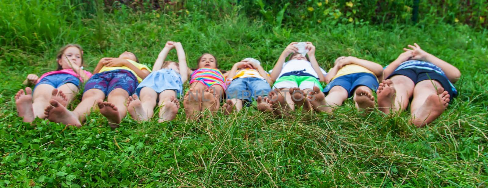 Children's feet lie on the grass. Selective focus. by yanadjana