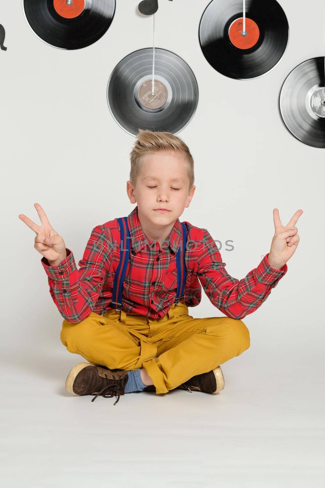 Retro disco 60s, 70s, 80s concept, funny boy wearing checked shirt, yellow trousers and stylish haircut on a background with music plate