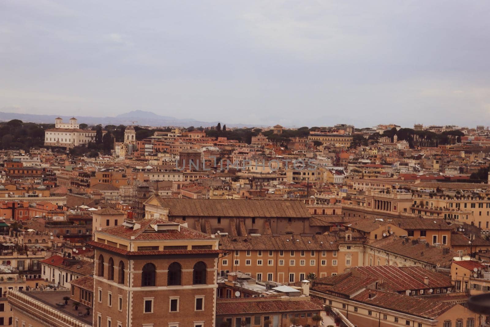 ROME, ITALY - February 05, 2022: Panoramic view around the Colosseum in city of Rome, Italy. Cold and gray sky in the background. Macro photography of the green parks with the old buildings.