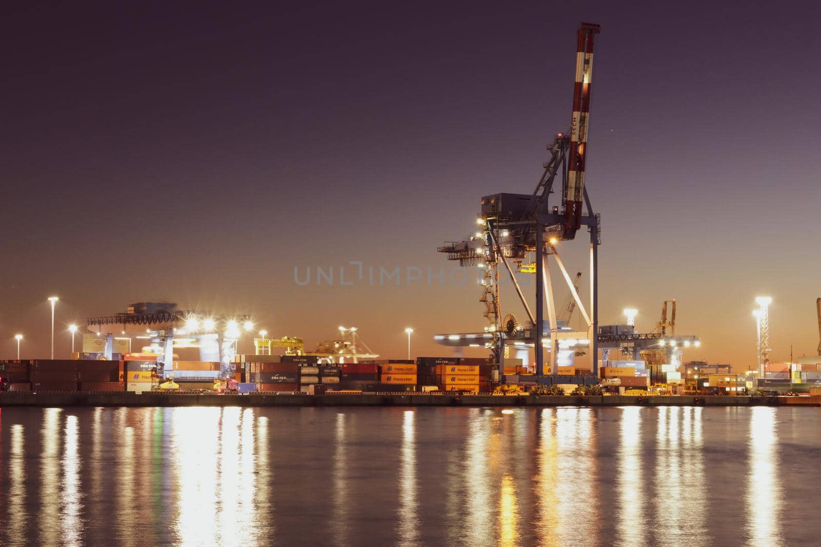 Genova, Italy - July 02, 2022: View of the city and the old harbor (Porto Antico) by night. City lights reflection over the water.