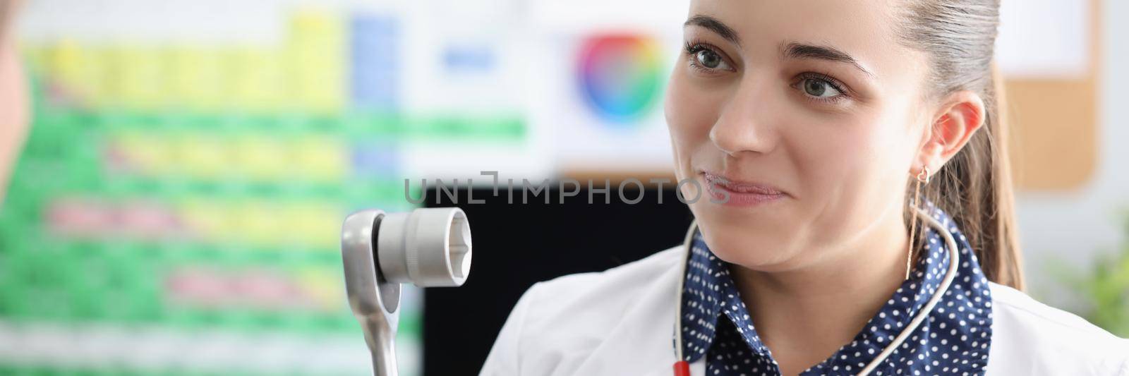 Portrait of smiling female doctor neuropathologist with equipment in clinic. Qualified woman in medical gown talk to patient on appointment. Health concept