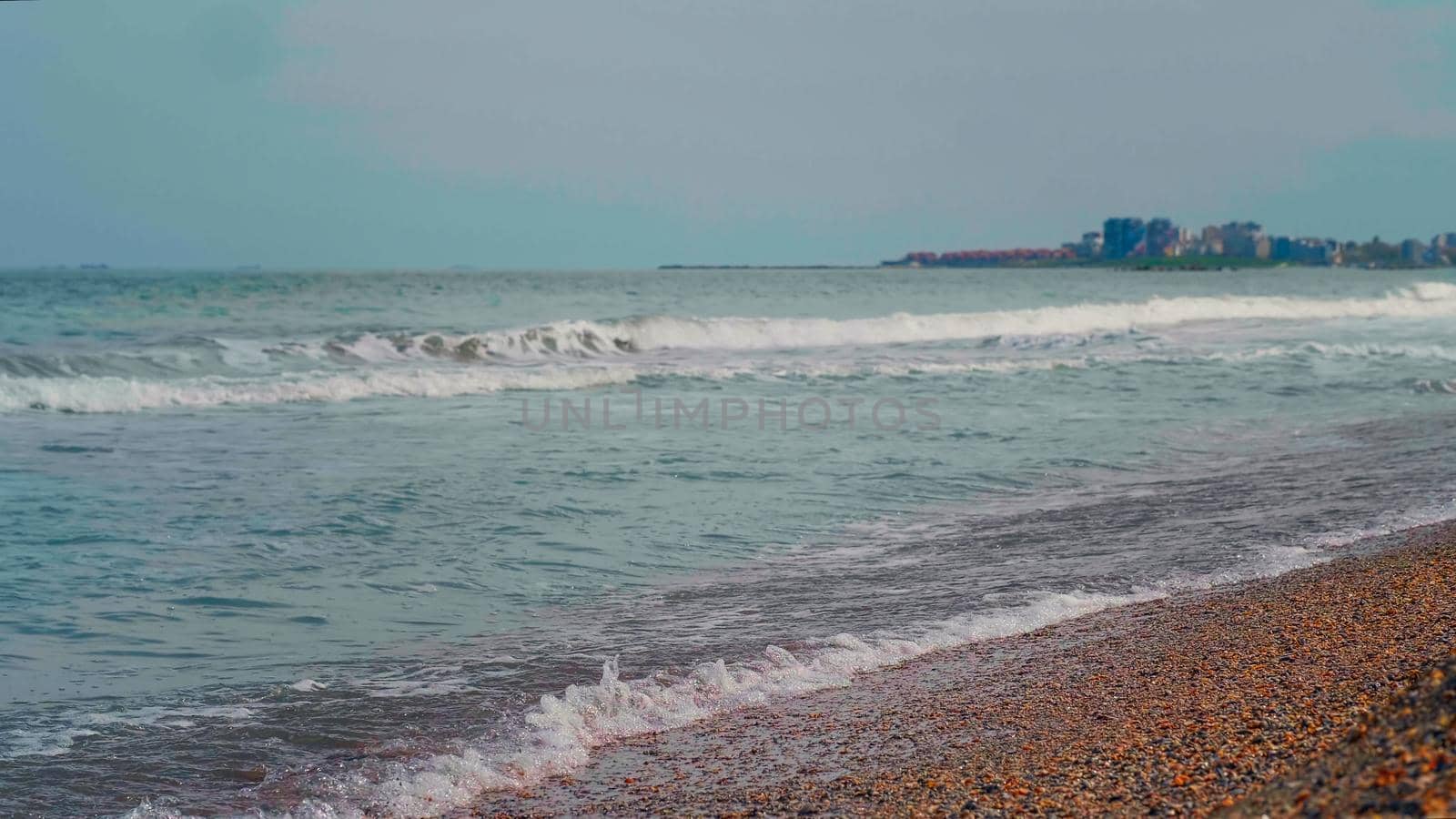 Beach sunny and windy day. Beautiful seascape. White foamy waves in the daytime. View of Black sea seachore.